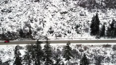A-Tracking-Perspective-of-a-Red-Jeep-on-Yellowhead-Highway-5-Through-the-Icy-North-Thompson-River-Valley-near-Kamloops,-Mesmerizing-Mountainous-Snow-covered-Landscape