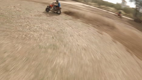 Motocross-riders-and-quad-bike-jump-small-ramp-on-dirt-track,-FPV