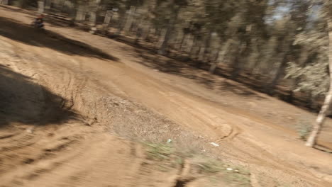 FPV-drone-follows-motocross-dirt-bike-racer-on-sandy-dirt-track