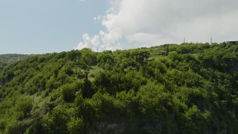 Rusty-material-aerial-tramway-on-wooded-cliff-in-Chiatura,-Georgia