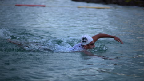 Male-athlete-swimming-freestyle-early-in-the-morning-in-the-sea-at-the-first-stage-of-the-triathlon-competition