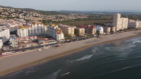 Aerial-view-of-the-hotels-area-next-to-the-beach-in-Peniscola,-moving-forward
