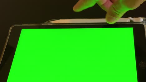 Man's-hands-holding-a-pen-securely-on-a-black-tablet-with-green-screen,-Chroma-key