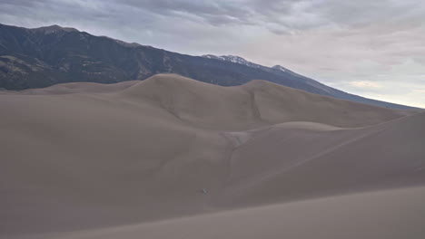 Tent-set-up-in-middle-of-sand-dunes-with-mountains-in-background