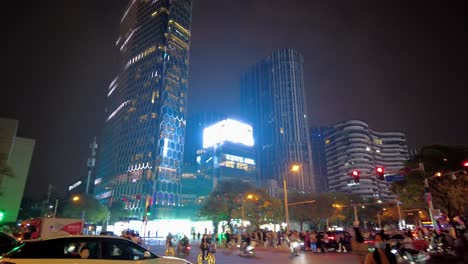Sanlitun-road-Beijing-4k---busy-night-street-with-people-riding-bikes-and-crossing-the-streets-and-beautiful-skyline-background