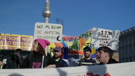 Activistas-Latinoamericanos-Cantando-En-Protesta-Por-La-Inflación-Económica-Con-La-Torre-De-La-Ciudad-Berliner-Fernsehturm-En-Segundo-Plano