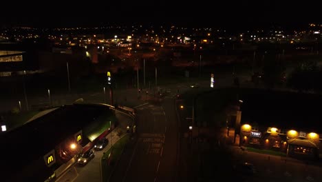 Northern-UK-town-McDonalds-fast-food-drive-through-at-night-Arial-view-pulling-backwards