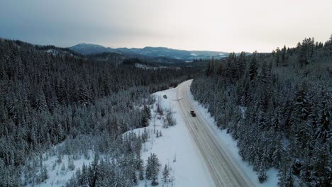 Snowy-Mountain-Adventure:-A-Following-Shot-of-a-Pickup-Truck-with-Trailer-Traveling-Along-Little-Fort-Highway-24-Surrounded-by-Majestic-Snow-Covered-Evergreen-Forests