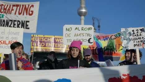 Manifestantes-Latinoamericanos-Con-Pancartas-De-Inflación-Económica-Se-Reúnen-Bajo-La-Torre-De-La-Ciudad-De-Berliner-Fernsehturm
