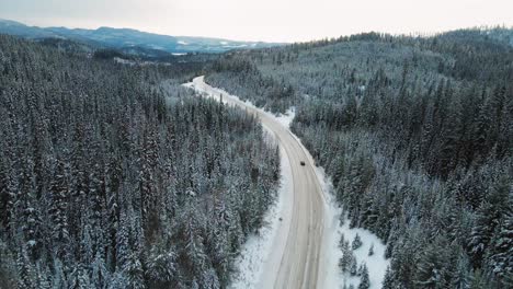 Black-Car-in-Snowy-Wilderness-of-Beautiful-British-Columbia,-Canada:-Peaceful-Winter-Scene-on-Little-Fort-Highway-24-in-a-Thick-Spruce-Forest-and-Mountains