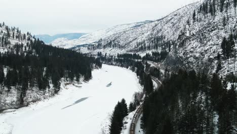 Experience-the-Beauty-of-Winter-in-British-Columbia:-Aerial-Shot-Follows-Freight-Train-Along-the-Frozen-North-Thompson-River-and-Yellowhead-Highway-5-Near-Kamloops