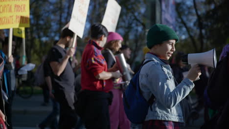 Young-people-protesting-on-street,-joyful-young-girl-talks-through-megaphone