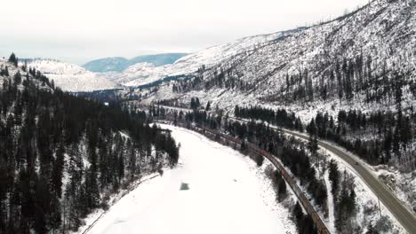 Güterzug-Fährt-Durch-Ein-Gefrorenes-Winterwunderland-In-British-Columbia:-Luftaufnahme-Folgt-Der-Fahrt-Entlang-Des-North-Thompson-River-Und-Des-Yellowhead-Highway-5