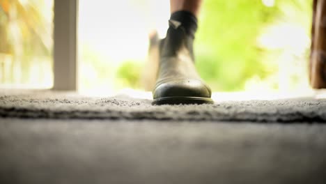 Man-entering-house-through-open-door,-taking-off-his-boots