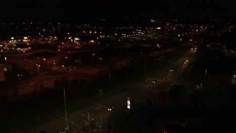 Night-flying-over-UK-town-highway-with-illuminated-street-lights-and-McDonalds-advertising-logo-aerial-view