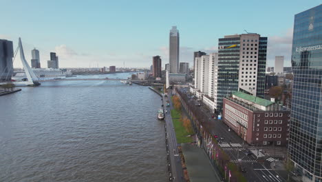 Kreuzfahrtschiff-Angedockt-Am-Flussufer-In-Der-Nähe-Der-Erasmusbrücke-Mit-Einer-Reihe-Zeitgenössischer-Gebäude-Am-Ufer-Der-Nieuwe-Maas-In-Rotterdam,-Niederlande