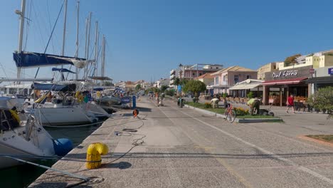 People-at-promenade-with-yacht-moored-and-raw-of-restaurants-and-cafes,-Preveza,-Greece