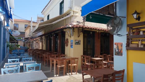 Mujer-Caminando-En-Un-Callejón-Con-Restaurante-De-Estilo-Mediterráneo-Y-Cafés-En-Preveza,-Grecia
