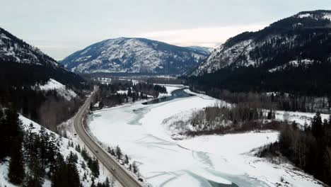 Cars-Driving-on-Yellowhead-Highway-5-Surrounded-by-Snow-Covered-Mountains-and-Beautiful-Forest-in-Little-Fort,-BC:-An-Aerial-View-with-Reverse-Flight
