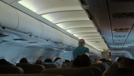 Man-walking-down-the-isle-on-an-Airbus-Airliner-cabin-in-flight---back-view