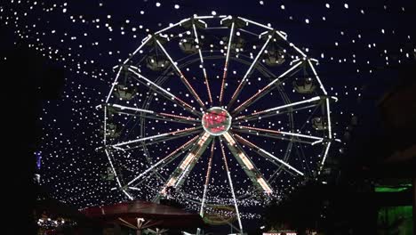 Fun-fair-at-a-christmas-amrket-in-kassel,-Germany-with-a-ferris-wheel-turning-during-tight-time