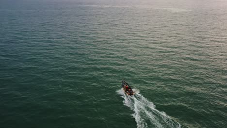 Toma-Aérea-De-Drones-Capturando-Un-Pequeño-Barco-De-Pesca-Tradicional-Navegando-En-El-Mar-Al-Atardecer