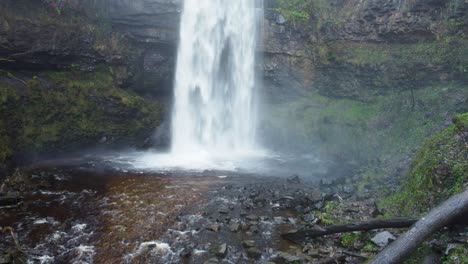 Wasserfall-Luftdrohne-Mit-Höhle-Dahinter-Und-Moosiger-Klippenwand-In-Wales-UK-4k
