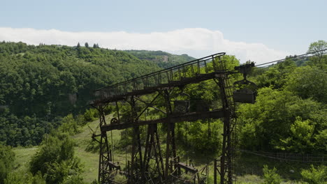 Old-rusty-freight-cableway-pylon-on-wooded-hillside,-Chiatura,-Georgia