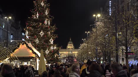 People-enjoying-Christmas-markets-with-decorated-tree-at-night,-Prague