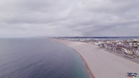 Drone-shot-flying-forwards-along-Chesil-beach-on-a-sunny-day,-Weymouth,-Dorset,-UK