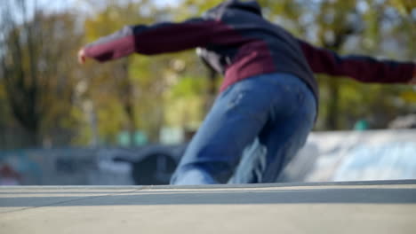 Rear-closeup-of-young-kid-dropping-down-ramp-with-skateboard,-slow-motion