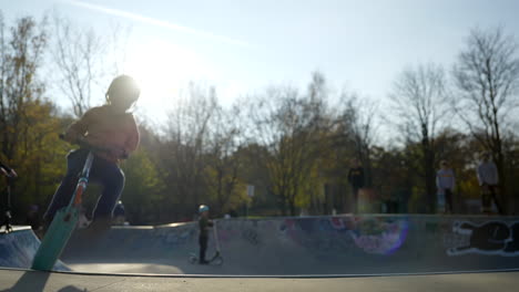 Niño-Pequeño-Saltando-Urbano-Skatepark-Bowl-Montar-Scooter-Cámara-Lenta
