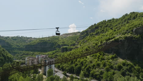 Rusty-material-ropeway-with-cargo-container-above-Chiatura-town-valley