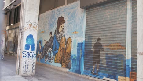 Spray-painted-mural-artwork-portraying-people-on-shopfront-urban-Athens