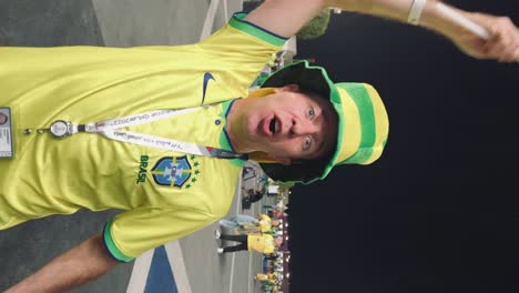 Vertical-video-of-Male-Brazilian-fan-celebrating,-waving-a-flag,-World-Cup-Qatar,-Slow-motion