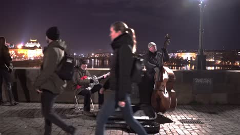 Dos-Músicos-Callejeros-Tocando-Música-En-El-Puente-Charles-Por-La-Noche,-Praga