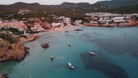 Stunning-Aerial-View-Of-Cala-Tarida-Coastline-With-Boats-Moored-In-Waters