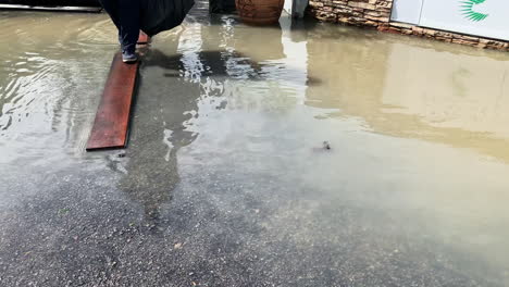 People-step-onto-a-wooden-platform-to-avoid-flooding-water-on-the-road