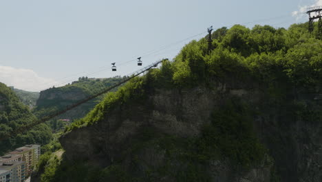Rusty-material-ropeway-with-cargo-containers-above-rock-cliff,-Georgia