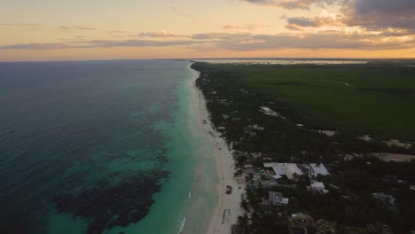 Luftaufnahme-Des-Sandigen-Akiin-strandes-Mit-Türkisfarbenen-Meereswellen-Der-Karibik-Und-Orangefarbenem-Sonnenuntergangshimmel-Am-Horizont