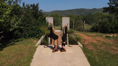 Couple-doing-acro-yoga-on-their-villa-property-in-Ibiza,-Spain-aerial-view
