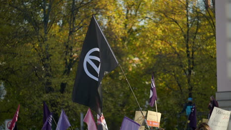 Slow-motion-black-anarchy-flag-waving-in-economic-inflation-protest-march,-Berlin