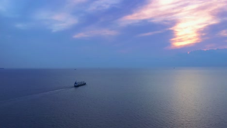 Filmische-Epische-Aufnahme-Eines-Schiffes,-Das-Im-Meer-In-Richtung-Sonnenuntergangshorizont-Segelt