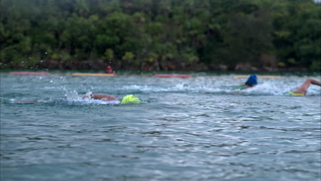 Slow-motion-Medium-shot-of-an-athlete-wearing-a-yellow-cap-and-goggles-swimming-in-a-triathlon-in-the-sea