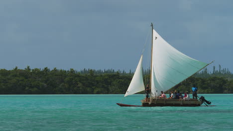 Tourists-having-a-sailing-adventure-on-an-outrigger-canoe-at-Upi-Bay-on-the-Isle-of-Pines,-New-Caledonia