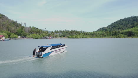Drone-shot-of-tourism-boat-speeding-on-the-waters-of-a-tropical-island,-Langkawi