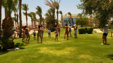 People-Enjoying-Their-Holiday-in-Hurghada,-Egypt-by-Dancing-with-Their-Kids-on-the-Grass