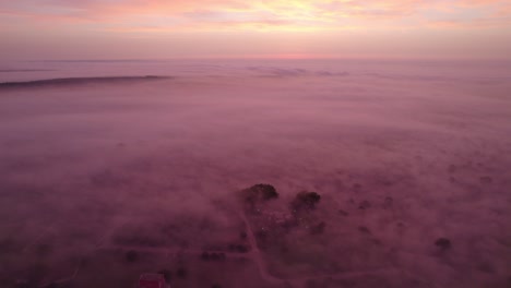 Heavenly-sunrise-above-mist-covered-rural-landscape,-aerial