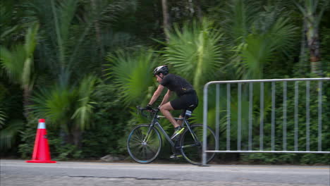 Slow-motion-of-a-male-athlete-wearing-a-black-suit-and-helmet-riding-his-bike-at-the-cycling-stage-of-a-triathlon