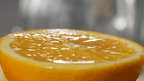 Macro-shot-of-Orange-juice-falling-on-fresh-orange-slice,-Super-slow-motion